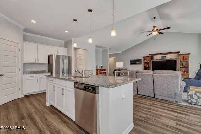 kitchen with a sink, light stone countertops, dark wood finished floors, stainless steel appliances, and a kitchen island with sink