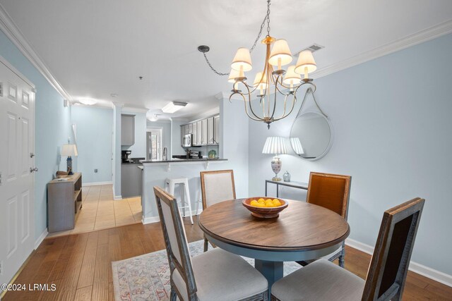 dining room with crown molding, a chandelier, and light wood-type flooring