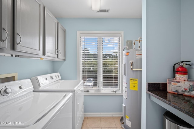 washroom featuring cabinets, washing machine and dryer, light tile patterned floors, and water heater