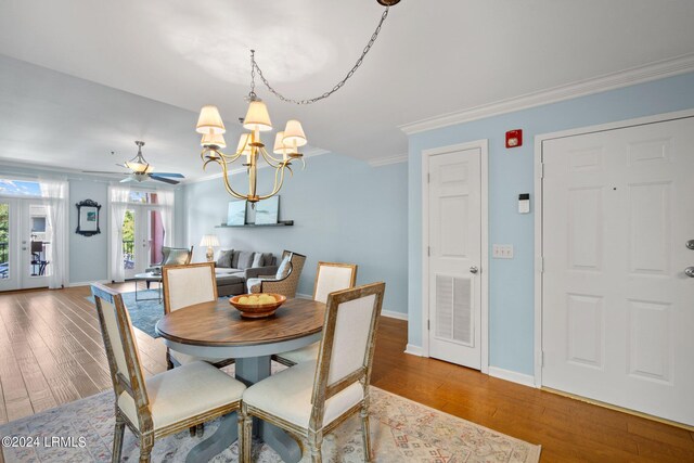 dining space featuring french doors, ornamental molding, ceiling fan with notable chandelier, and hardwood / wood-style floors