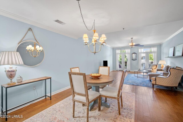 dining room with ceiling fan with notable chandelier, ornamental molding, and hardwood / wood-style floors