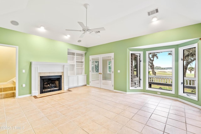 2 Doe Pt, Dataw Island, SC 29920 - unfurnished living room featuring light tile patterned flooring, a ceiling fan, built in features, a tiled fireplace, and french doors