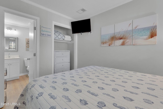 bedroom featuring crown molding, ensuite bathroom, sink, and light wood-type flooring