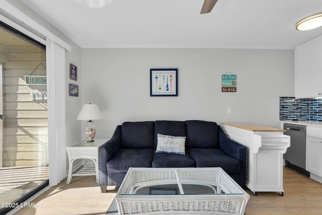 living room with ornamental molding, light hardwood / wood-style floors, and ceiling fan