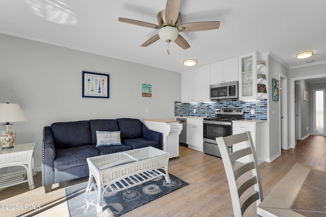 living room with ceiling fan, ornamental molding, and light hardwood / wood-style floors