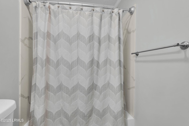 bathroom with shower / bath combination with curtain, a textured ceiling, and toilet