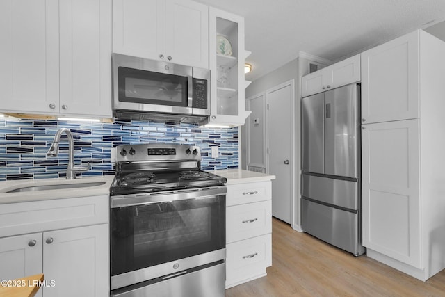 kitchen with sink, stainless steel appliances, tasteful backsplash, light hardwood / wood-style floors, and white cabinets