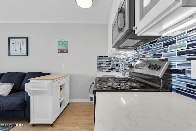 kitchen with sink, white cabinets, backsplash, crown molding, and light hardwood / wood-style flooring