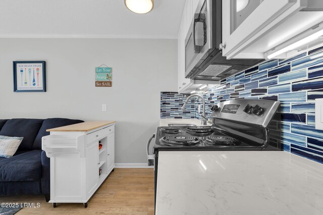 kitchen with sink, white cabinets, backsplash, crown molding, and light hardwood / wood-style flooring