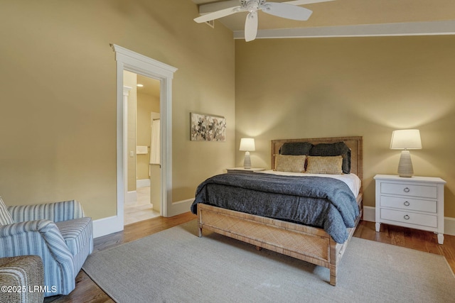 bedroom with beam ceiling, wood-type flooring, ceiling fan, and ensuite bath