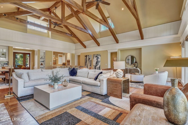 living room with ceiling fan, high vaulted ceiling, beam ceiling, and light hardwood / wood-style floors