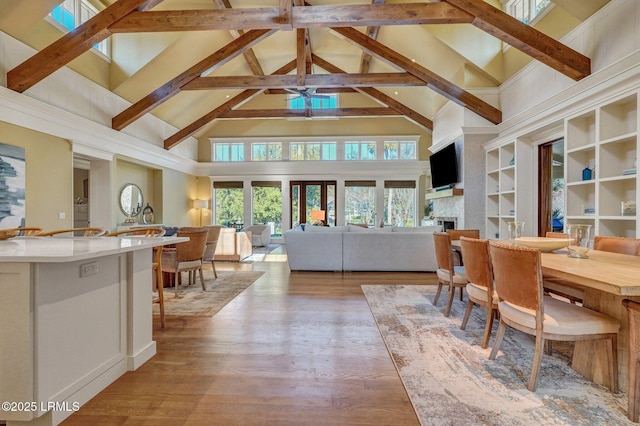 dining space with beamed ceiling, ceiling fan, high vaulted ceiling, and light wood-type flooring