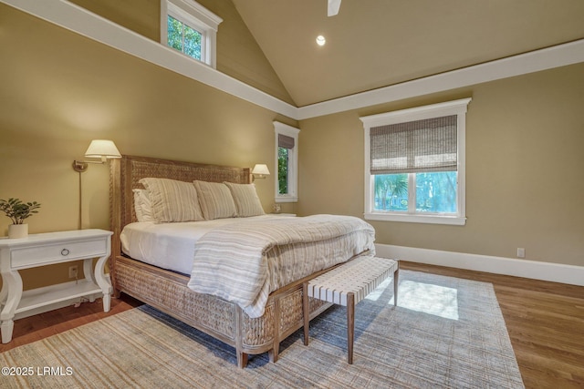 bedroom featuring wood-type flooring, high vaulted ceiling, and multiple windows