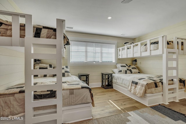 bedroom featuring wooden walls and light hardwood / wood-style floors