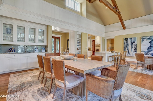 dining space with french doors, high vaulted ceiling, light hardwood / wood-style floors, and sink