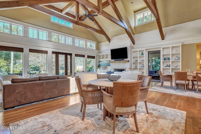 dining space with beam ceiling, high vaulted ceiling, and light hardwood / wood-style floors