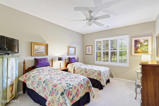 bedroom featuring light colored carpet, a textured ceiling, and ceiling fan