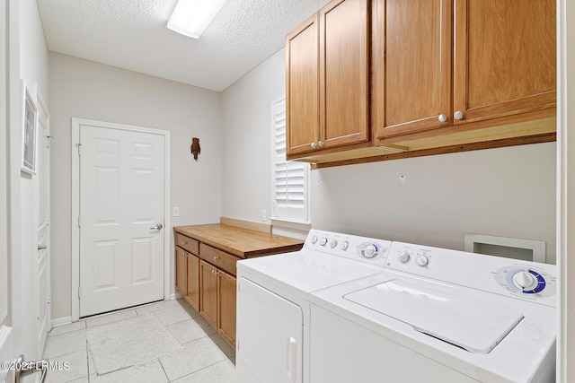 washroom featuring washer and dryer, light tile patterned floors, cabinets, and a textured ceiling