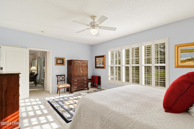 carpeted bedroom featuring ceiling fan and a textured ceiling