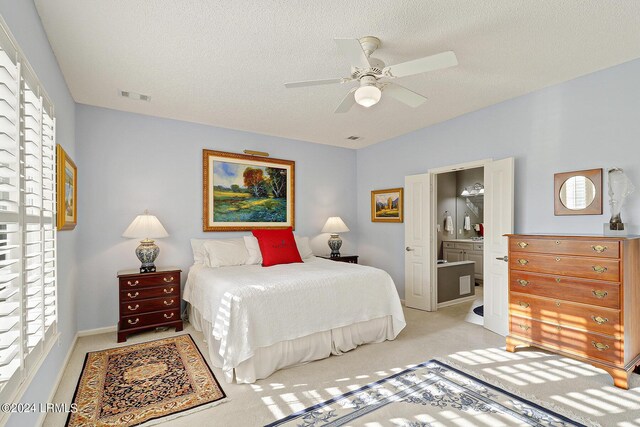 carpeted bedroom with ceiling fan, ensuite bath, and a textured ceiling