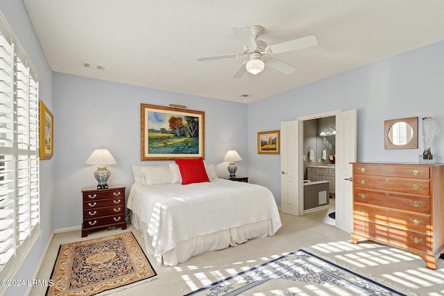 carpeted bedroom with ceiling fan, ensuite bath, and a textured ceiling