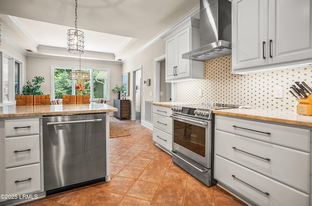 1 Wild Magnolia Ct, Okatie, SC 29909 - kitchen featuring appliances with stainless steel finishes, wall chimney range hood, a tray ceiling, a chandelier, and white cabinetry