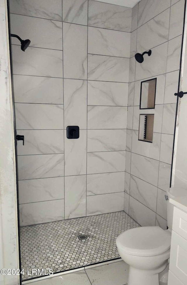 bathroom with a tile shower and toilet