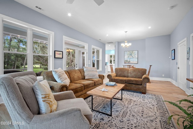 living room with ceiling fan with notable chandelier and light hardwood / wood-style floors