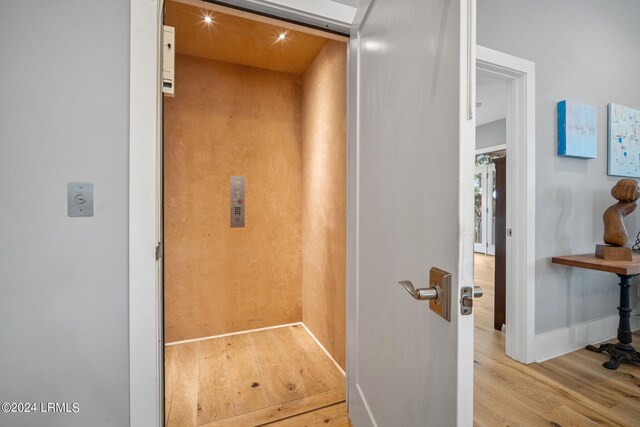 interior details featuring elevator and hardwood / wood-style floors