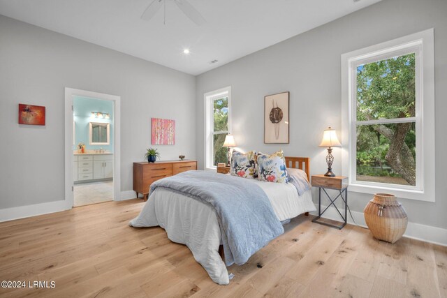 bedroom with multiple windows, light wood-type flooring, ceiling fan, and ensuite bath