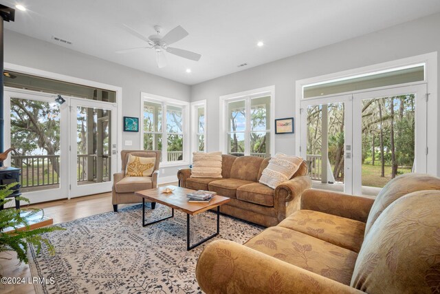 living room featuring a wealth of natural light, light hardwood / wood-style flooring, french doors, and ceiling fan