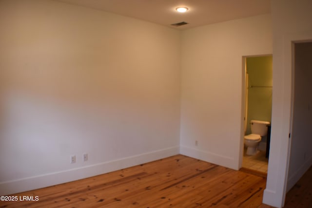 unfurnished bedroom featuring hardwood / wood-style flooring and ensuite bathroom