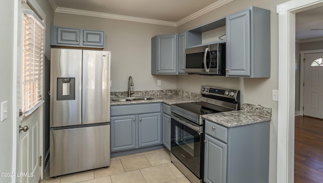 kitchen featuring light tile patterned flooring, sink, gray cabinetry, ornamental molding, and stainless steel appliances