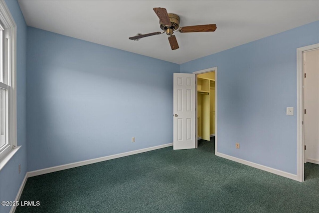 10 Broomfield Ln, Beaufort, SC 29907 - unfurnished bedroom with a spacious closet, dark carpet, baseboards, and a ceiling fan