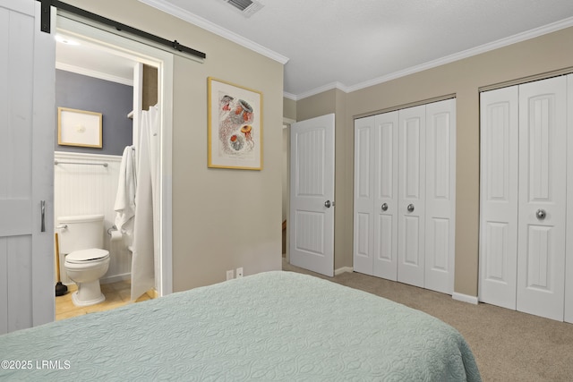 96 Mathews Dr Unit 145, Hilton Head Island, SC 29926 - bedroom with multiple closets, a barn door, ornamental molding, carpet, and connected bathroom