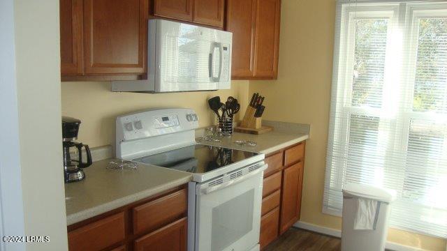 kitchen featuring white appliances and dark hardwood / wood-style flooring