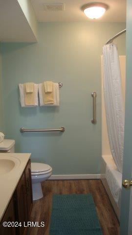 full bathroom featuring vanity, hardwood / wood-style floors, shower / tub combo with curtain, and toilet