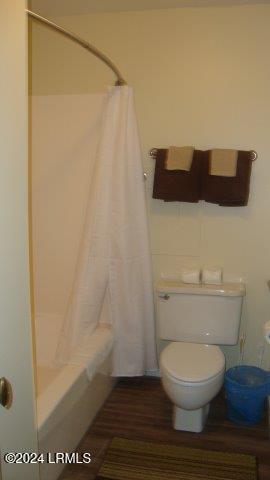 bathroom with shower / bathtub combination with curtain and toilet