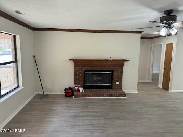 unfurnished living room with ornamental molding, a textured ceiling, light wood-type flooring, and a fireplace