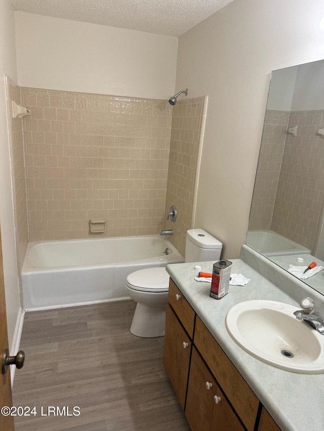 full bathroom featuring toilet, tiled shower / bath, a textured ceiling, vanity, and hardwood / wood-style flooring