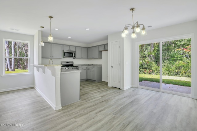 kitchen featuring a peninsula, appliances with stainless steel finishes, visible vents, and gray cabinetry