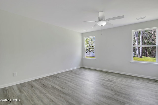 empty room with a ceiling fan, baseboards, visible vents, and wood finished floors