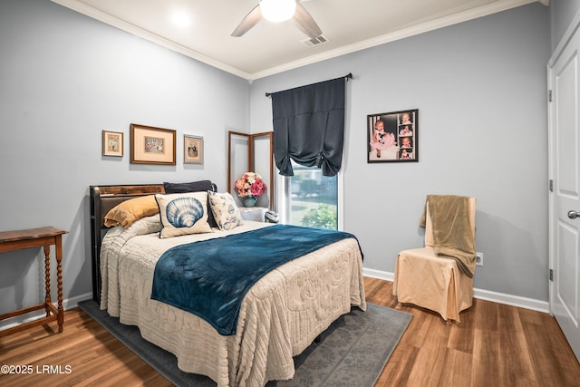 bedroom with wood finished floors, ornamental molding, visible vents, a ceiling fan, and baseboards