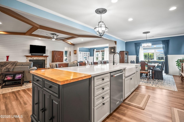kitchen featuring stainless steel dishwasher, butcher block counters, a sink, white cabinetry, and open floor plan