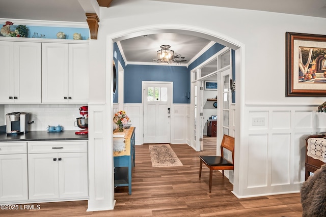 interior space with crown molding, a decorative wall, and arched walkways