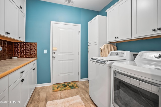 washroom featuring cabinet space, washing machine and dryer, light wood finished floors, and baseboards