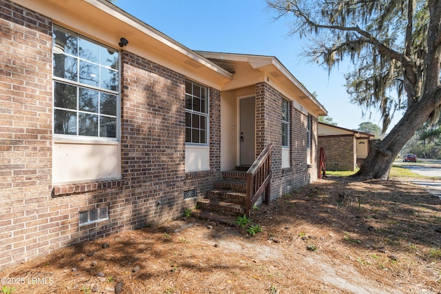 view of property exterior with brick siding and crawl space