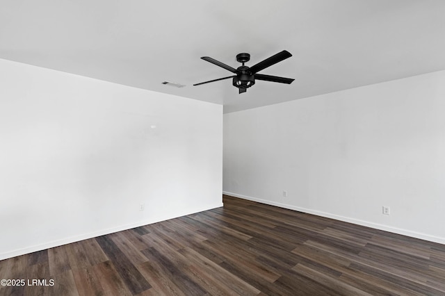 spare room with dark wood finished floors, visible vents, a ceiling fan, and baseboards