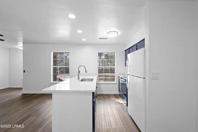 kitchen featuring stainless steel range with electric cooktop, dark wood-style floors, freestanding refrigerator, and a sink