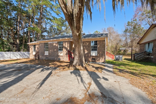 view of front facade with crawl space, brick siding, and fence